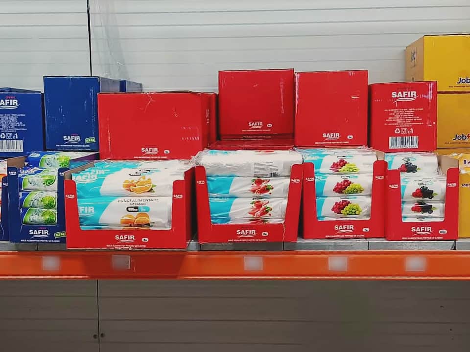 Raft cu pungi alimentare pe rolă, în cutii de expunere albastre, roșii și galbene