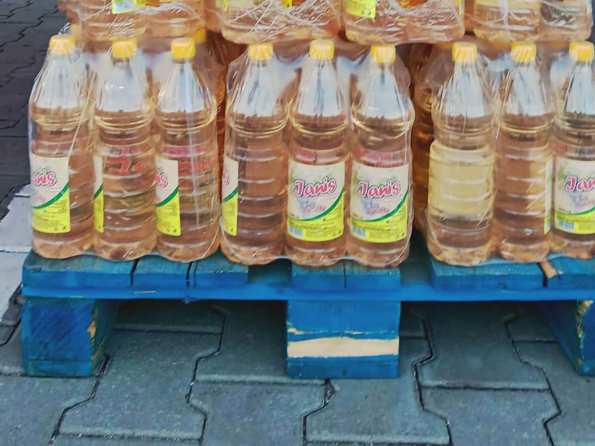 Baxuri de sticle cu etichetă galbenă, stivuite pe un palet albastru în fața magazinului