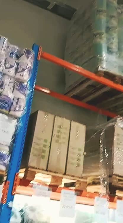 Rafturi industriale portocalii și albastre, cu baxuri de hârtie și cutii de carton pe paleți, pe mai multe niveluri